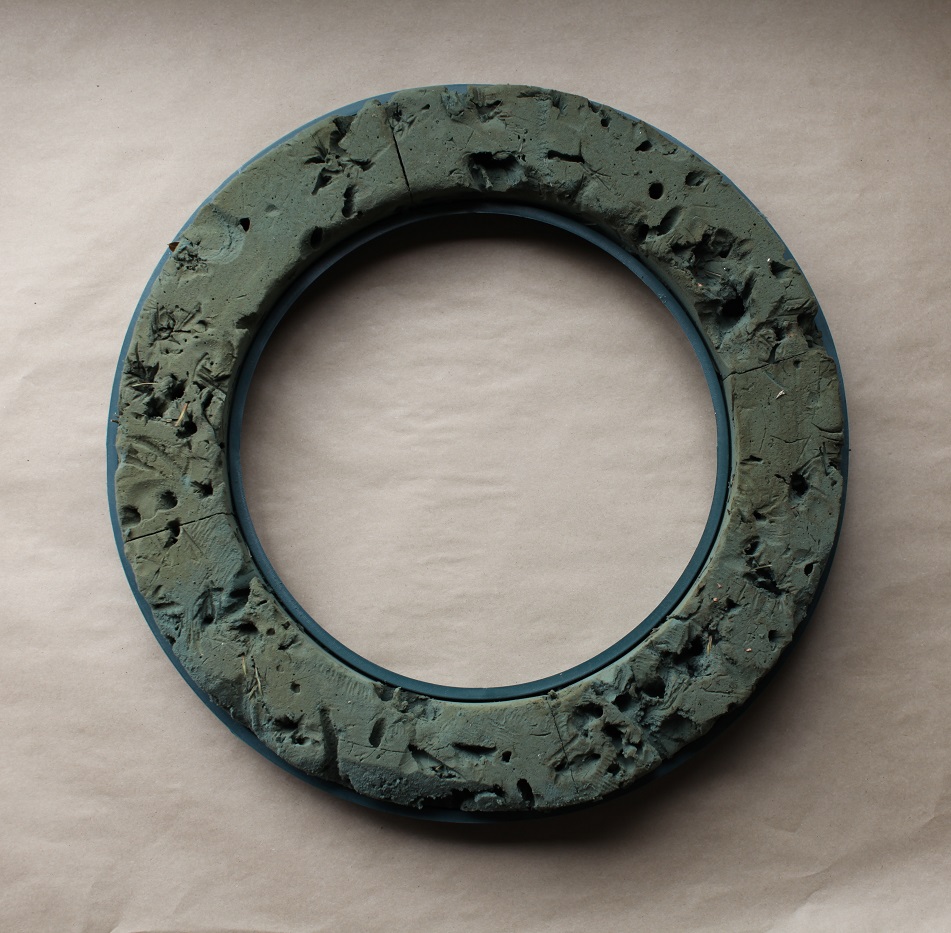 A ring of used, green floral foam in a hard plastic base.